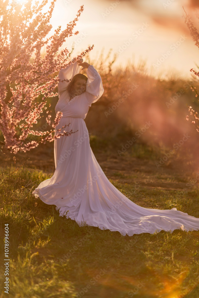 Woman blooming peach orchard. Against the backdrop of a picturesque peach orchard, a woman in a long white dress enjoys a peaceful walk in the park, surrounded by the beauty of nature. Woman blooming peach orchard. Against the backdrop of a picturesque peach orchard, a woman in a long white dress enjoys a peaceful walk in the park, surrounded by the beauty of nature.