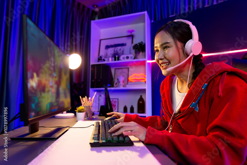 Host channel of young beautiful Asian gaming streamer playing fighting Moba at battle arena game on pc screen with multiplays, wearing pastel headphone at neon digital light modern room. Stratagem. photo