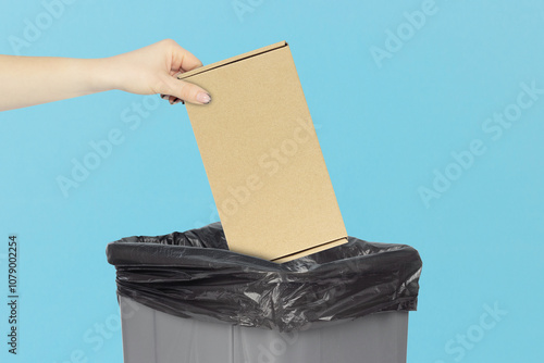 throw a cardboard parcel box into the trash bin, hold a cardboard parcel box in your hand in front of the trash bin, cardboard recycling concept photo