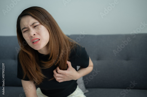 Asian woman having chest pain problem. Chest pain has many causes, like issues in your heart, lungs or digestive system. photo