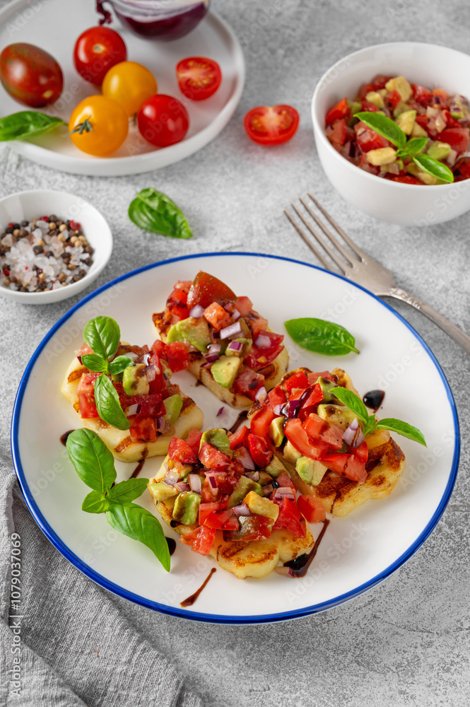 Grilled halloumi cheese with tomatoes, avocado, onion and balsamic sauce on a plate on a concrete background. Grilled halloumi cheese with tomatoes, avocado, onion and balsamic sauce on a plate on a concrete background.