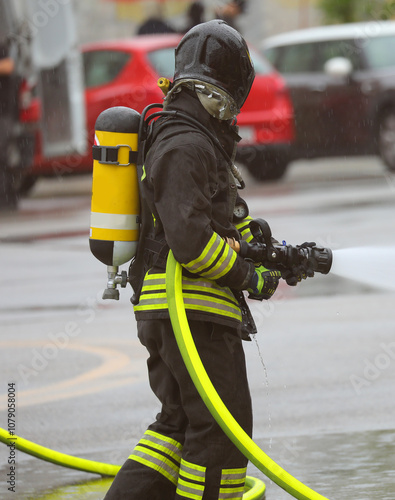 firefighter wearing helmet and oxygen tank with self contained breathing apparatus spraying foam photo