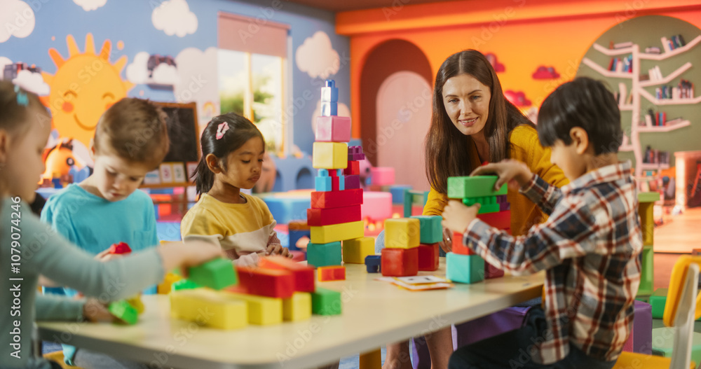 Fototapeta premium Group of Adorable Creative Kids Using Colorful Building Blocks to Play Together. Cheerful Female Teacher Spending Productive Time in Daycare, Teaching Multiethnic Kids in Preschool