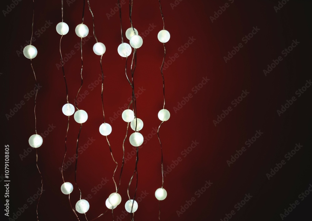 Obraz premium Glowing electric garland on red background in the dark. Minimalistic festive background