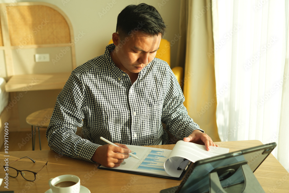 Focused young asian man sitting and reading electronic document, checking the data analyst to send to his business partner. Concentrated smart ambitious business man preparing research during his trip Focused young asian man sitting and reading electronic document, checking the data analyst to send to his business partner. Concentrated smart ambitious business man preparing research during his trip