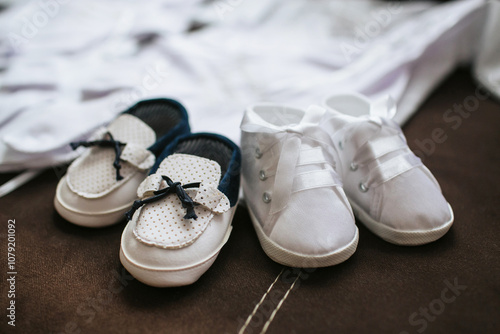 Adorable small brown suede baby shoes on fabric for a christening. Soft footwear for twins, perfect for a special ceremony. Elegant outfit for two. Children's fashion and footwear. photo