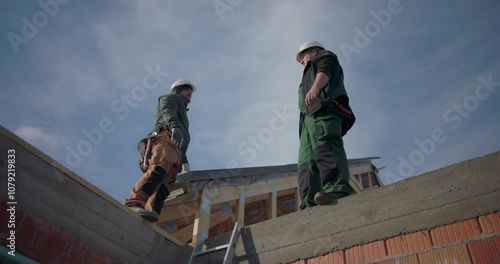 Wallpaper Mural Two construction workers discussing project on rooftop, wearing helmets, teamwork in residential building project, focus on communication and collaboration Torontodigital.ca