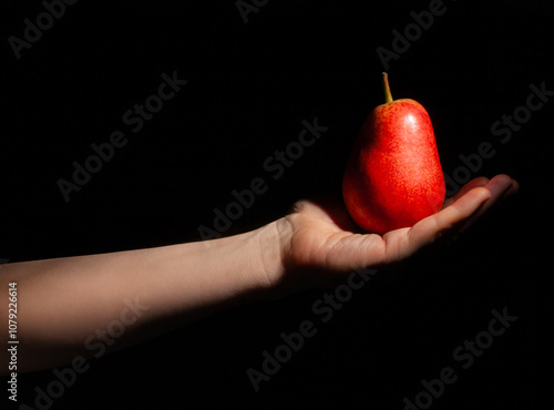 red pear in hand on black background photo