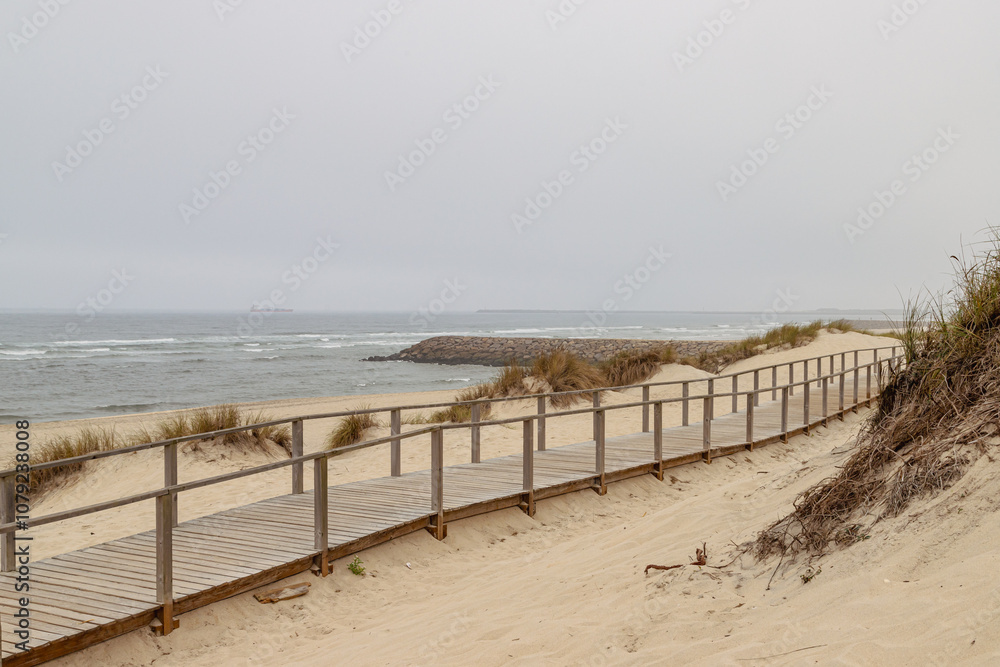 Beach in cloudy weather. Wooden path on the ocean shore. Portuguese Way Beach in cloudy weather. Wooden path on the ocean shore. Portuguese Way