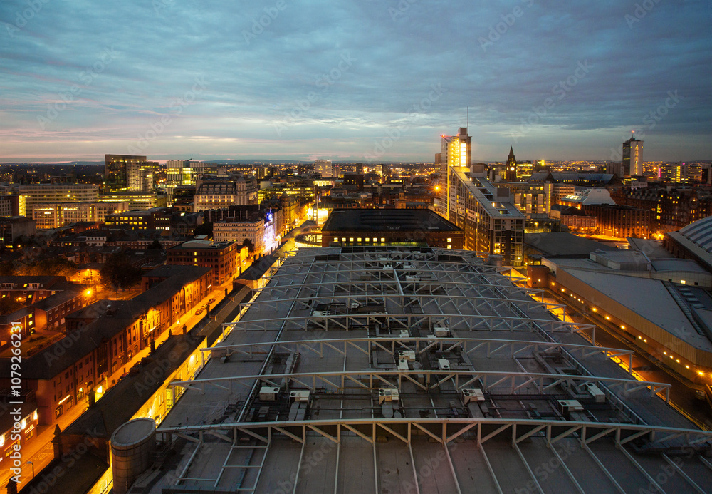 Aerial view looking over roof of the Gmex conference centre and skyline of Manchester at dusk