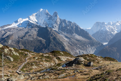 Hikers walking along a wooden walkway in Aiguilles Rouges nature reserve with a large mountain in the background photo