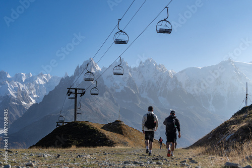 Two male hikers walking below a still chair lift in Aiguilles Rouges nature park, Chamonix, French Alps. Chamonix Aiguilles in the background. photo