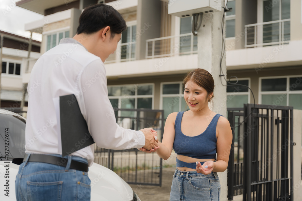 Obraz premium Happy New Car Owner: A smiling young woman receives her car keys from a sales representative, marking a joyous moment of new beginnings and financial achievement. 