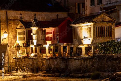 Cuadro en lienzo four horreos by the sea lit up at night in combarro, galicia