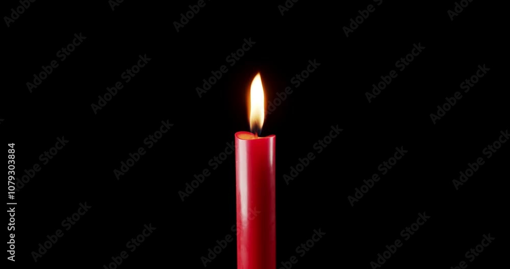 A single red candle burning. Isolated candle burning with dark background. Red paraffin candle with yellow shades burns on a black background. Background or illustration of remembrance or celebration. A single red candle burning. Isolated candle burning with dark background. Red paraffin candle with yellow shades burns on a black background. Background or illustration of remembrance or celebration.
