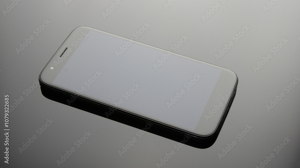 Modern smartphone with blank screen on reflective surface Modern smartphone with blank screen on reflective surface