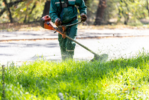 Foto A landscaper using a string trimmer to maintain grass along a park pathway durin