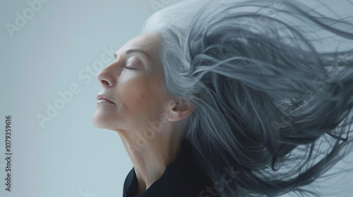 Elegant older woman with flowing gray hair against a minimalistic background photo