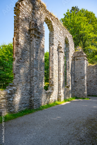 Remnants of the Hoerbrunn Church stand amidst lush greenery in Hopfgarten, Austria. The ancient stone walls reflect history under the clear blue sky, inviting exploration and reflection. photo