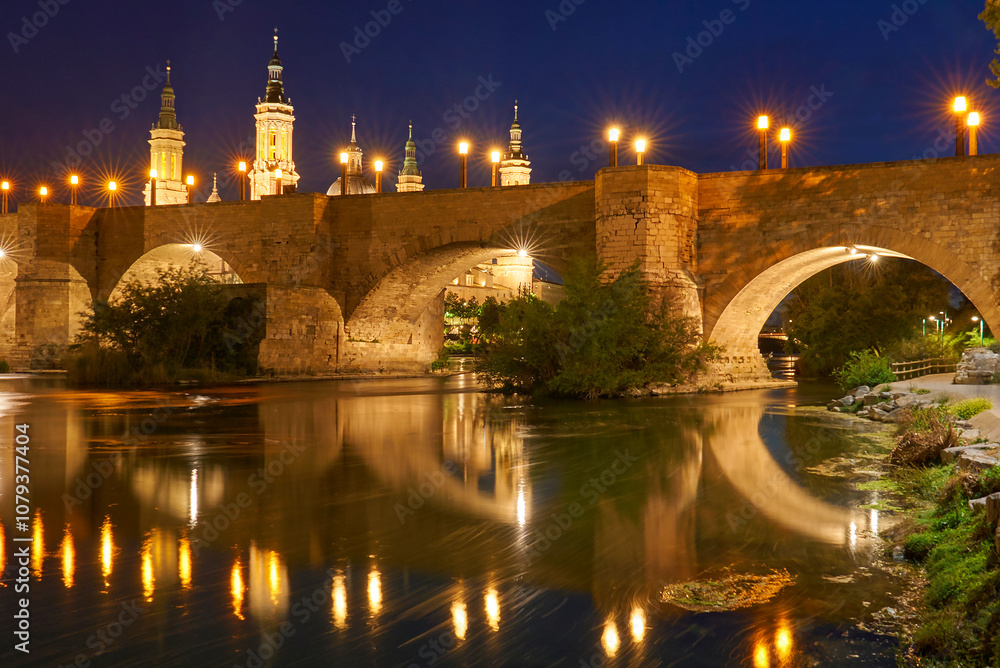 View on the Stone Bridge and Basilica of Our Lady of the Pillar on the banks of Ebro river at night. Zaragoza, Spain View on the Stone Bridge and Basilica of Our Lady of the Pillar on the banks of Ebro river at night. Zaragoza, Spain