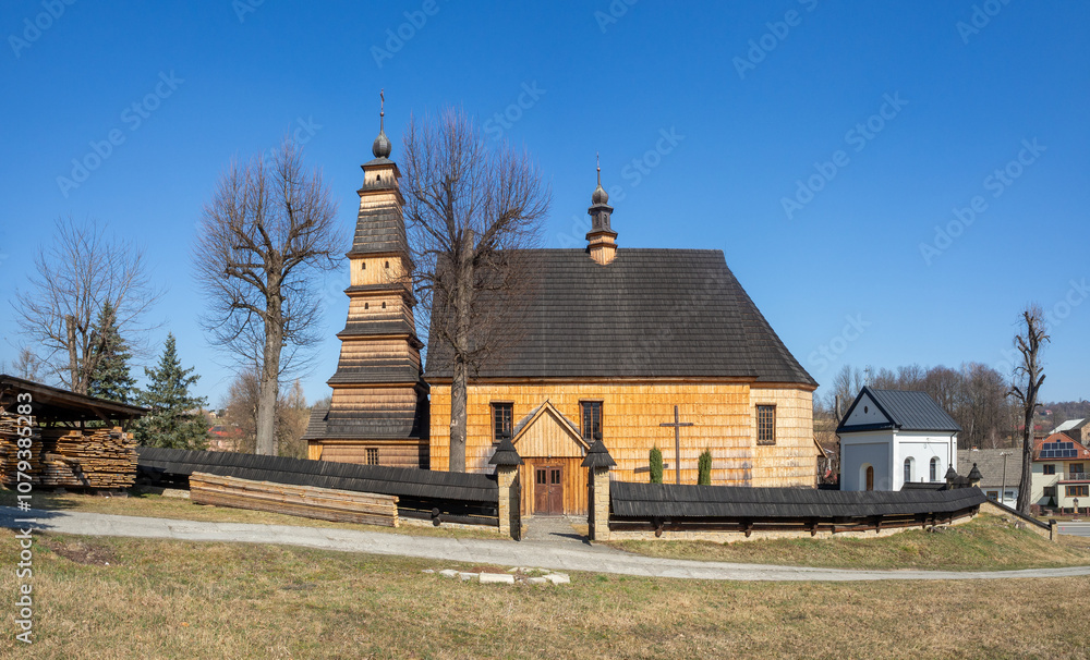 Old wooden church of Saint Andrew in Roznowice in Poland. Built in 18th century. High tower. Roof covered with shingles