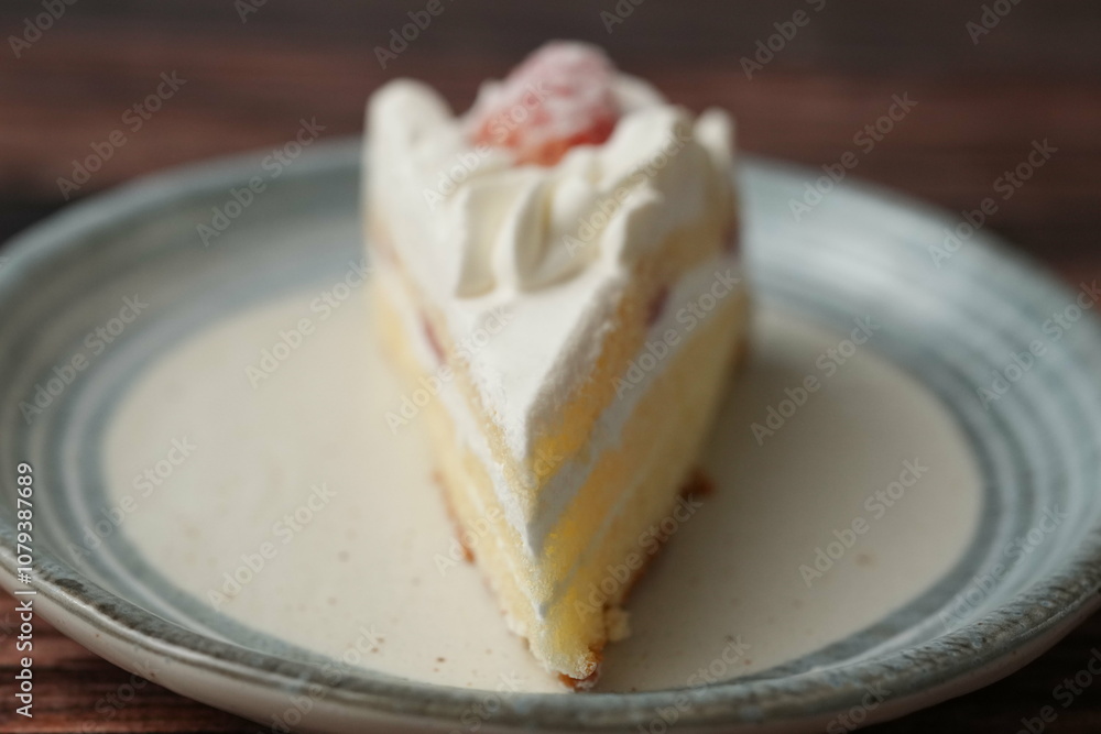 One small Japanese strawberry shortcake on a stylish Japanese plate on a brown wooden deck One small Japanese strawberry shortcake on a stylish Japanese plate on a brown wooden deck