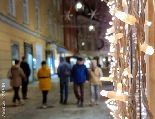 People walking on a street with beautiful Christmas decorations at night, in the city center of Graz, Styria region, Austria. Selective focus