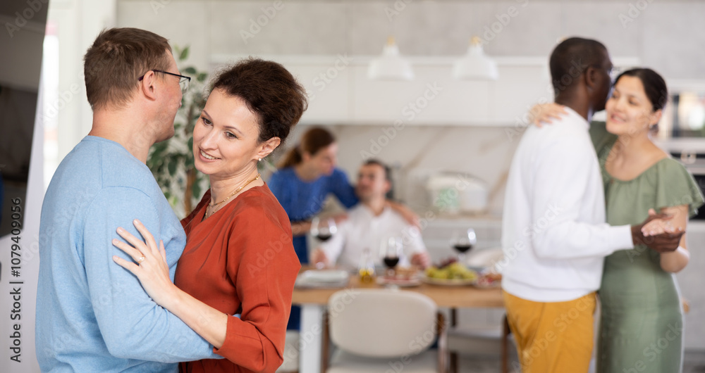 Happy middle-aged men and women doing slow dance in pairs during cozy get-together with friends Happy middle-aged men and women doing slow dance in pairs during cozy get-together with friends