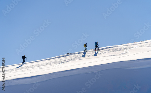 Hikers Trekking Across Snowy Slope Under Clear Blue Sky