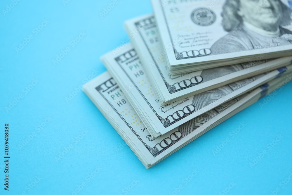 Big amount of hundred dollar bills in thick stack lies on bright blue color paper background Big amount of hundred dollar bills in thick stack lies on bright blue color paper background