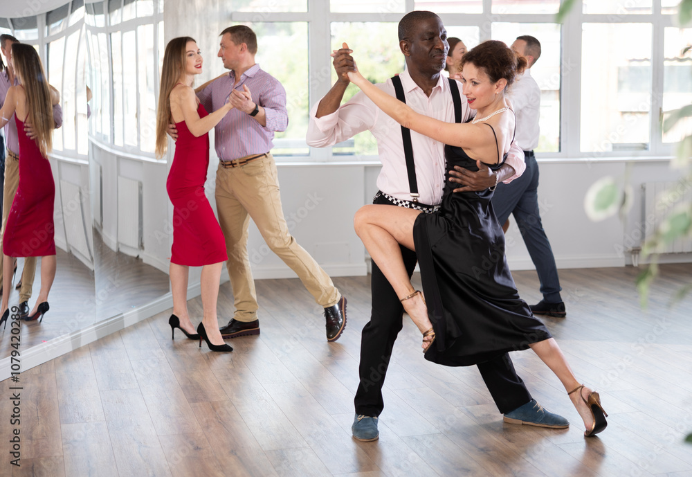 Naklejka premium Active middle-aged lady training waltz in pair with man in dance-hall during dancing classes