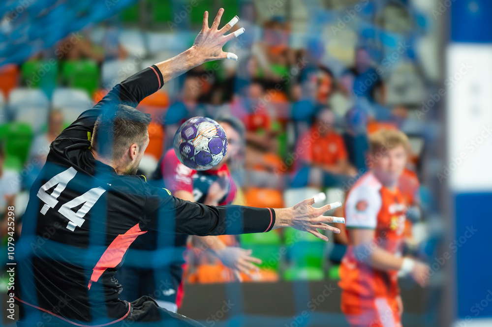 Handball goalkeeper and ball flying to the goal during handball game.