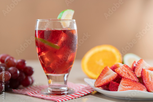 Close-up of glass cup with homemade summer wine in foreground next to plate of chopped strawberries