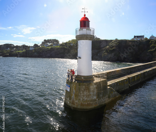 Trois personnes adultes et un enfant au pied d'un phare de Belle-Ïle-en-Mer (Le Palais) font signe à un ferry qui arrive au port photo