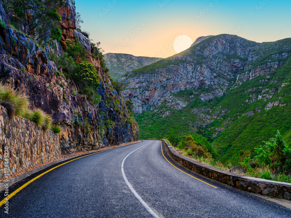 Sun setting behind the mountain on a winding road through Langeberg Mountains, Suurbraak, Overberg, Western Cape, South Africa