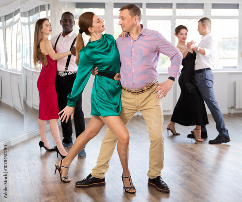 Active middle-aged lady training waltz in pair with man in dance-hall during dancing classes