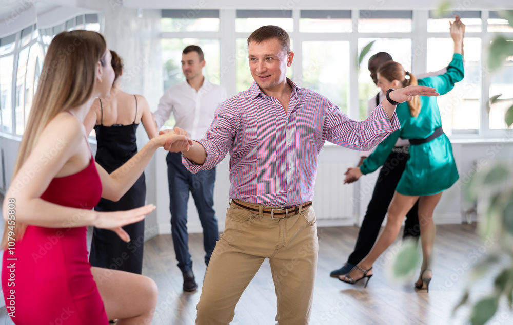 Positive woman and man dancing foxtrot in pair during group dance party Positive woman and man dancing foxtrot in pair during group dance party