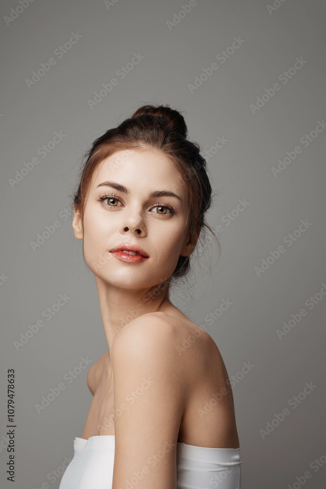 Beautiful young woman in white dress posing for the camera on gray background Beautiful young woman in white dress posing for the camera on gray background