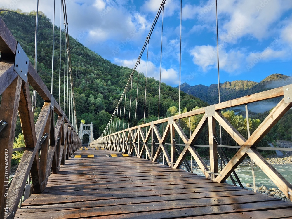 Obraz premium Wooden suspension bridge over the river in the mountains. Beautiful landscape.