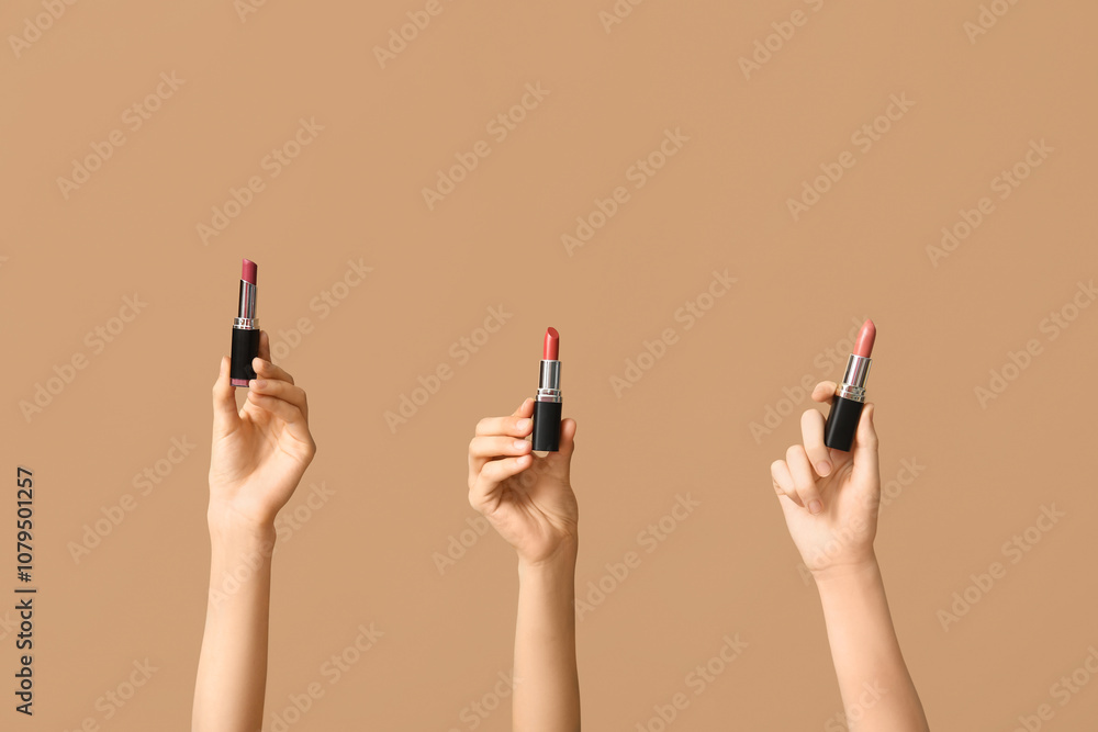 Female hands with different lipsticks on brown background Female hands with different lipsticks on brown background