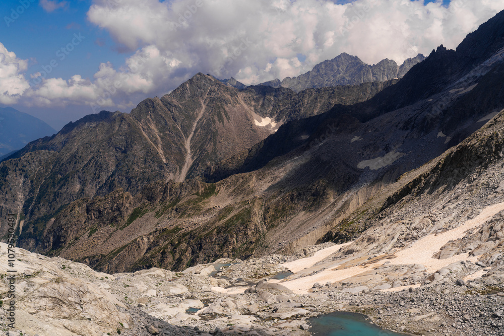 Dramatic view of mountainous landscape featuring steep rocky slopes and turquoise alpine lakes. Rugged peaks under a sky filled with dynamic clouds, capturing the raw beauty of the alpine wilderness Dramatic view of mountainous landscape featuring steep rocky slopes and turquoise alpine lakes. Rugged peaks under a sky filled with dynamic clouds, capturing the raw beauty of the alpine wilderness
