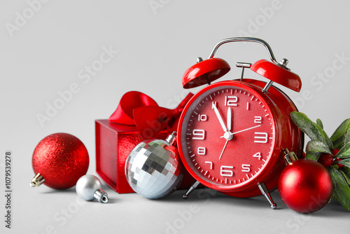 Beautiful composition with alarm clock, gift box and Christmas decor on light background photo