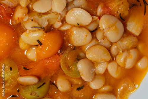 close up of butter beans in broth with rosemary, cherry tomato photo