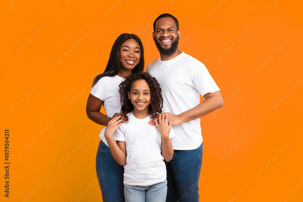 Happy Loving Family. Portrait of African American man, woman and girl standing isolated on yellow studio wall. Smiling husband and wife posing with daughter at camera. Togetherness And Bonding Concept Happy Loving Family. Portrait of African American man, woman and girl standing isolated on yellow studio wall. Smiling husband and wife posing with daughter at camera. Togetherness And Bonding Concept