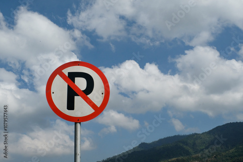 No Parking sign post with cloudy sky and hill background. A round signpost on the side of the road. Copy Space. Graphic Resources. Road Traffic Signs. Red Signs