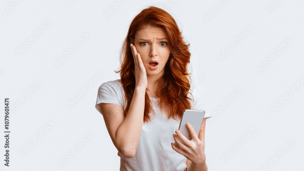 Oops, Bad News. Shocked Teen Girl Holding Cellphone Reading Embarassing Message Standing Over White Studio Background. Panorama, Copy Space Oops, Bad News. Shocked Teen Girl Holding Cellphone Reading Embarassing Message Standing Over White Studio Background. Panorama, Copy Space