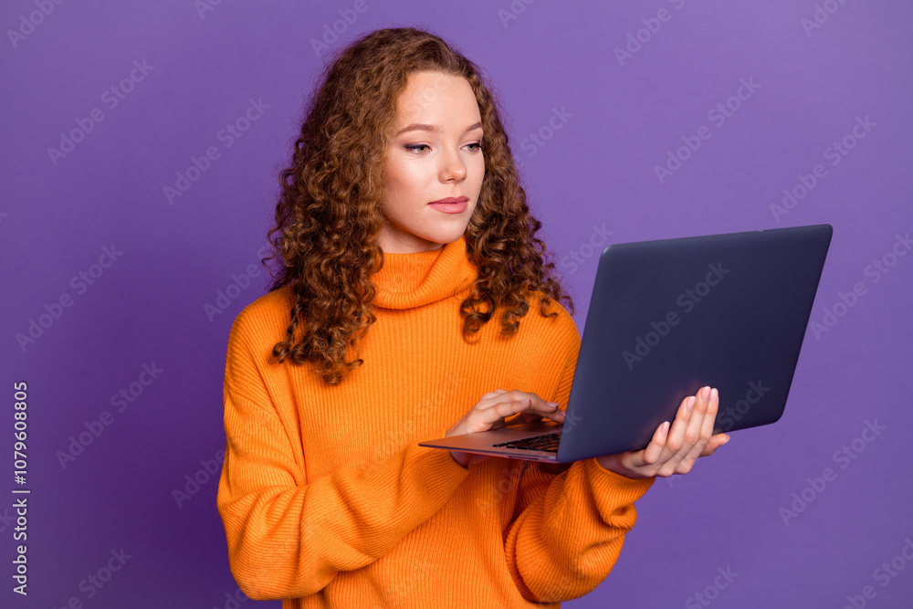 Naklejka premium Portrait of pretty young girl use laptop wear orange sweater isolated on purple color background