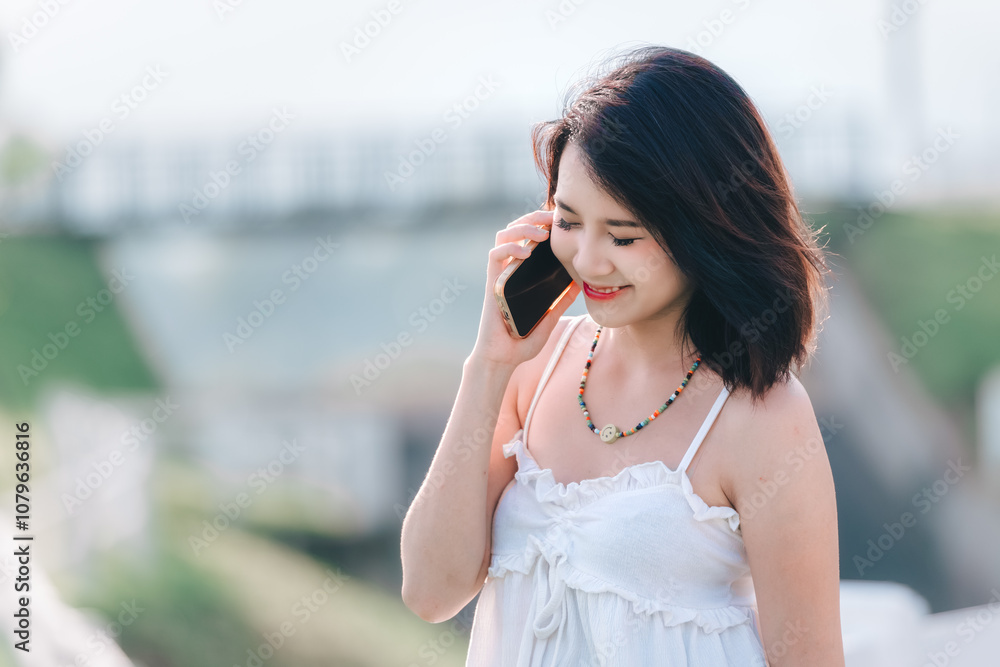 Young woman engaged in a joyful phone conversation at a scenic outdoor location Young woman engaged in a joyful phone conversation at a scenic outdoor location
