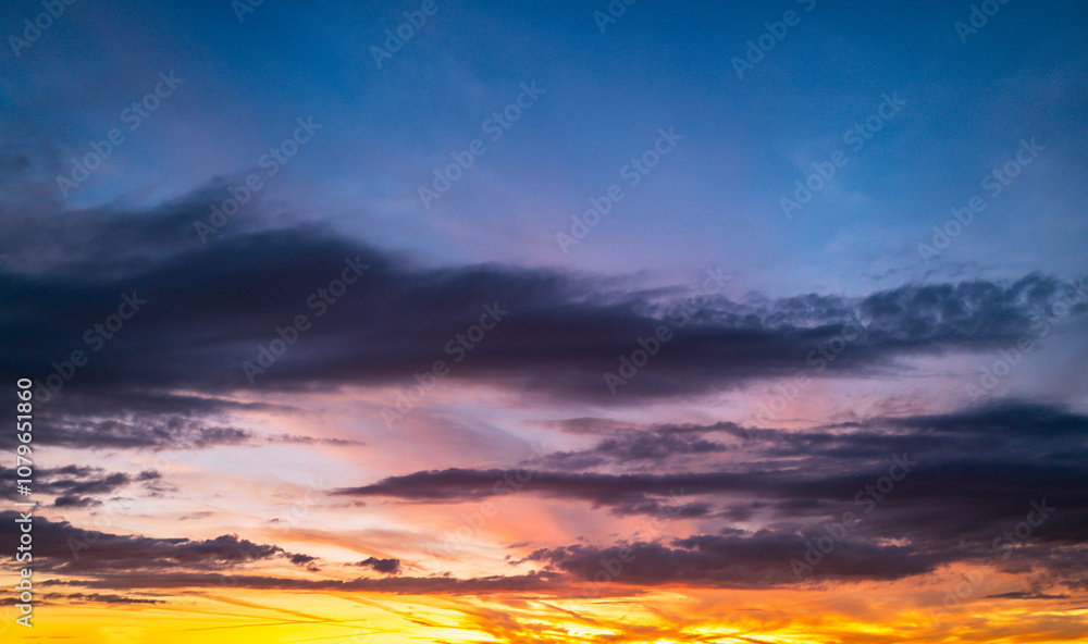 Obraz premium Sunset background. Dramatic majestic scenery sunset. Sky with clouds in sunset sky light background. Sunrise with clouds in various shapes. Calm sunset sky and sun through clouds over.