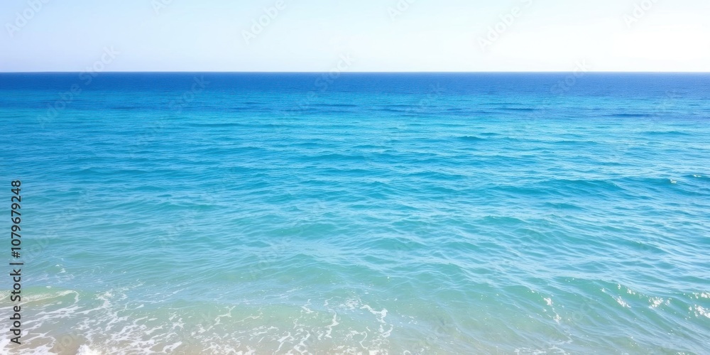 Obraz premium A serene image of a vast ocean, with clear blue water stretching out to the horizon under a clear sky and gentle waves lapping at the shore, nature, water
